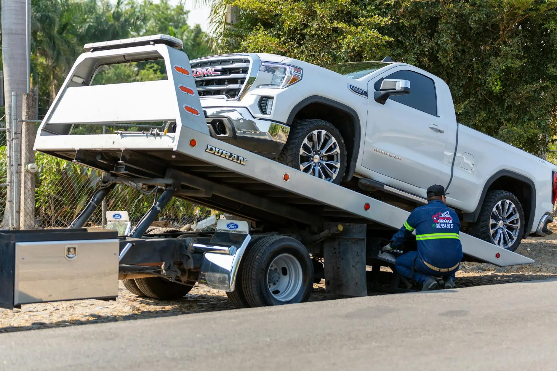 A clean, modern tow truck operator professionally greeting a customer in a well-lit Brentwood parking lot.